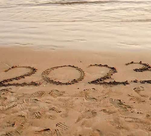 Picture of the Year 2023 carved in sand at a beach.